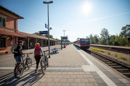 Zwei Radfahrer reisen am Bahnhof Altötting an.