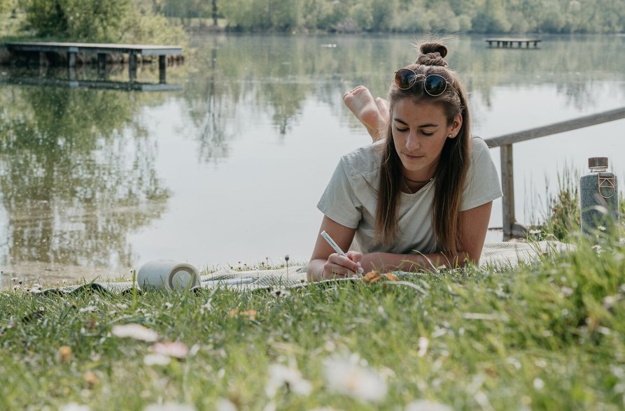 Frau liegt auf der Liegewiese am Peracher Badesee, © Inn-Salzach Tourismus